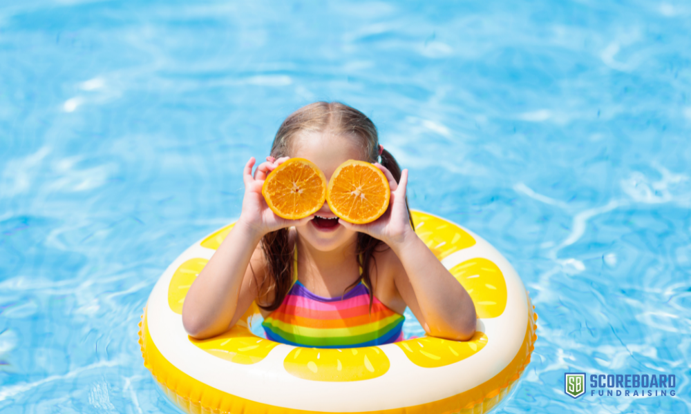 Girl in swimming pool with oranges.