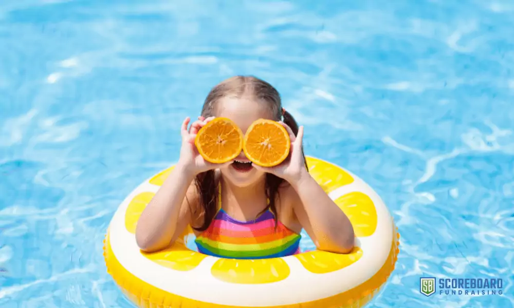 Girl in swimming pool with oranges.